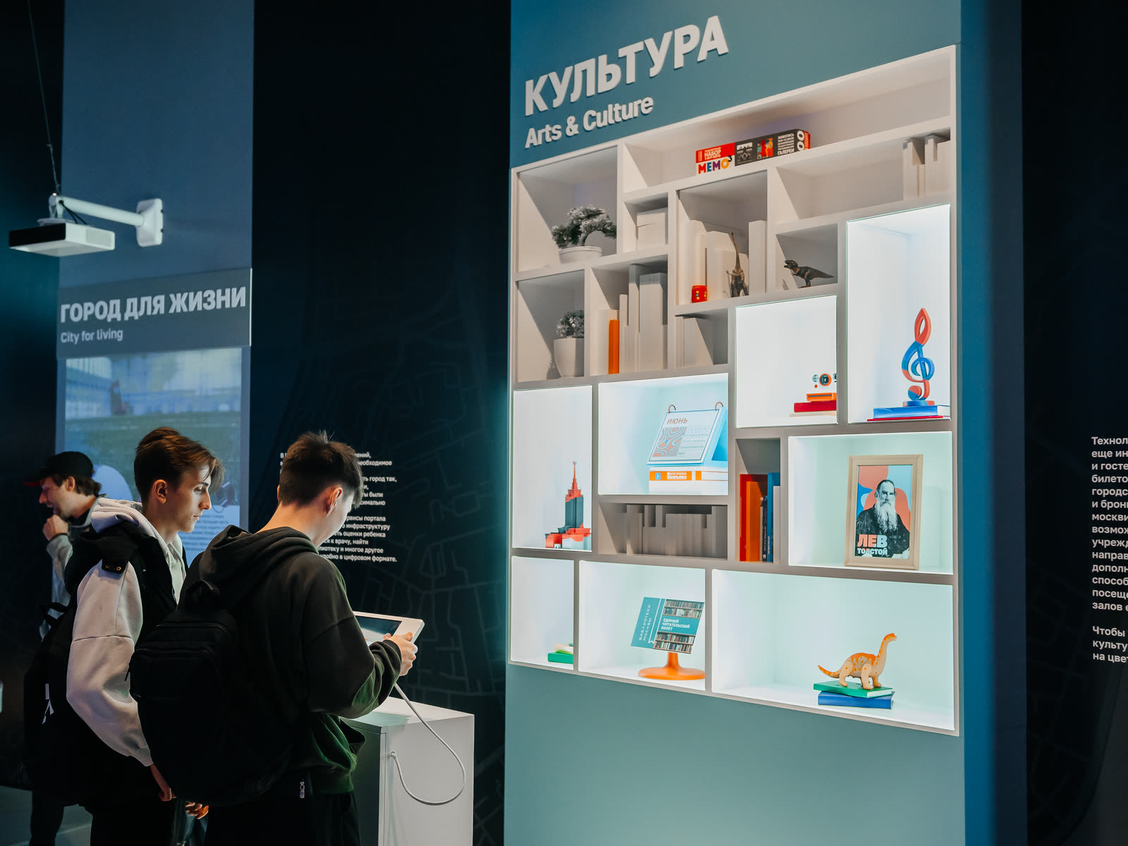 Посетители у стены «Город для жизни» и стеллажа «Культура»